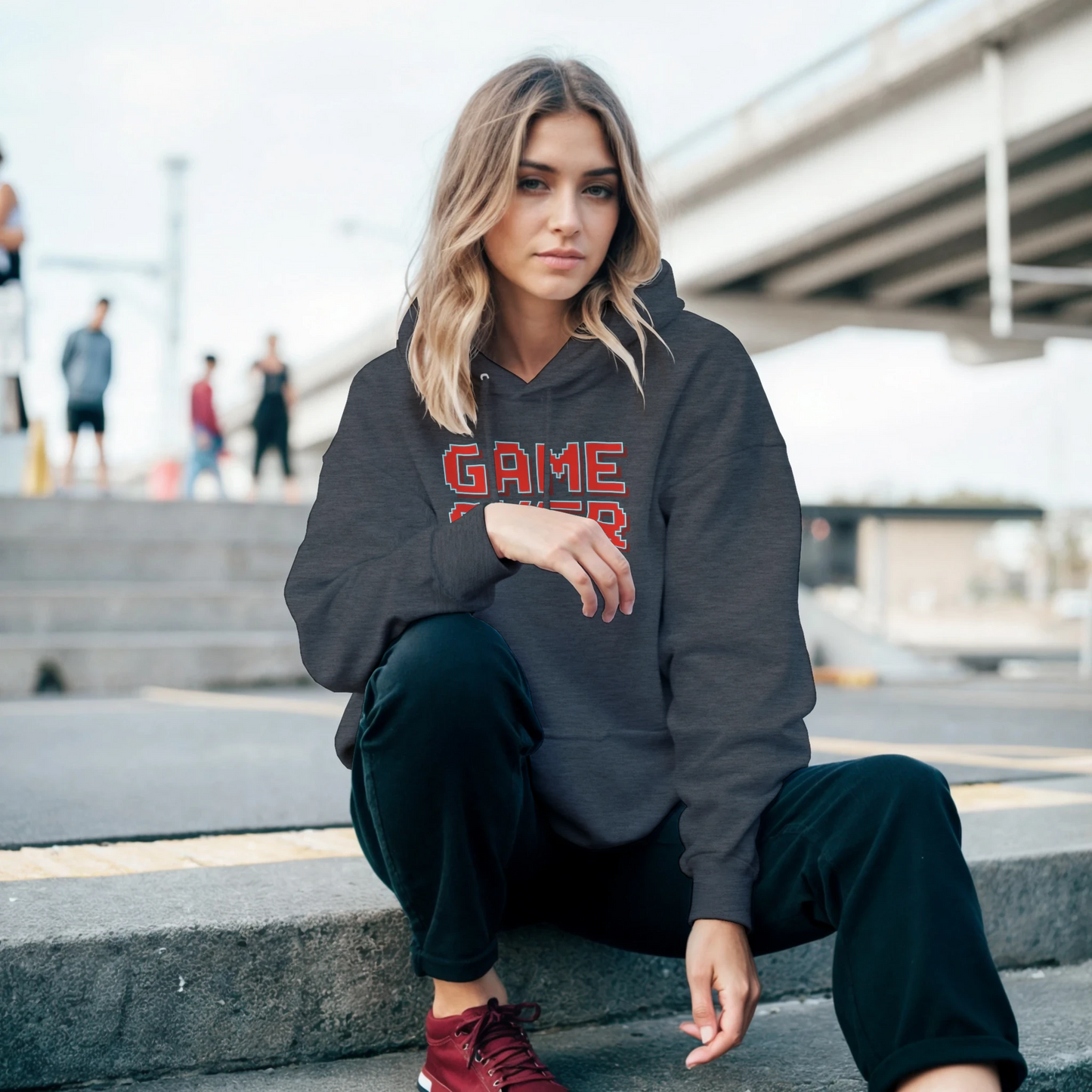 mujer sentada vistiendo la sudadera “Game Over” de FandomFit, prenda retro gamer ideal para looks casual